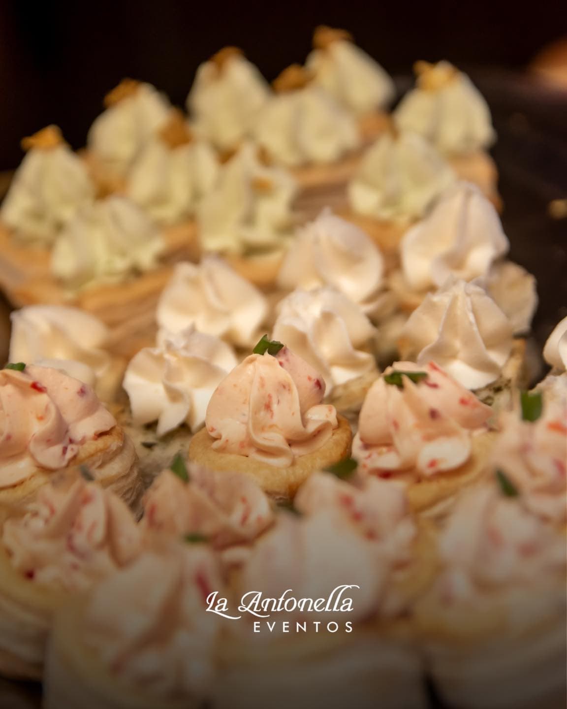 Bandejas de bocaditos de copetín servidos, volovanes con mousse de jamón y de salmón espolvoreados con ciboulette.
