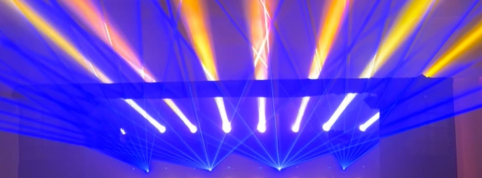 El rig de luces montado sobre la pista, con los haces azules y ámbar abriéndose desde la estructura.