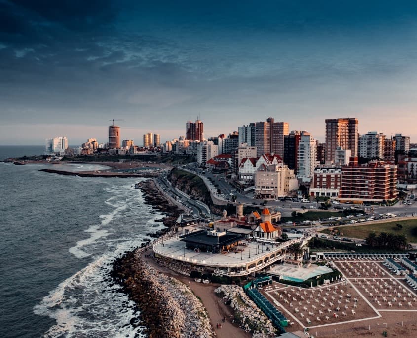 El Torreón del Monje visto desde arriba, sobre las rocas de Playa Grande, con la costa y los edificios de Mar del Plata detrás.