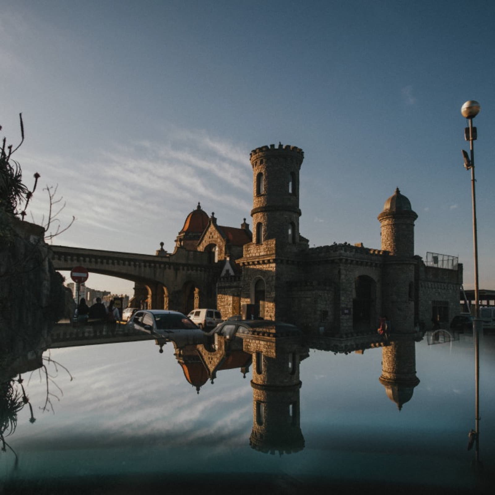 El castillo del Torreón reflejado en el agua de la rambla al atardecer, con las torres recortadas contra el cielo.